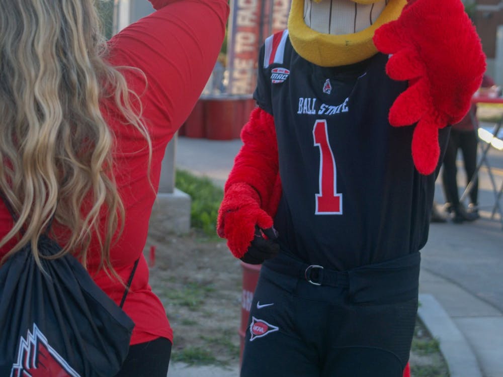 Ball State's mascot, Charlie Cardinal, entertains a group of students by placing a necklace on his head at the Food Truck Festival in the Village in Muncie, IN, on Monday, Oct. 18th, 2021.