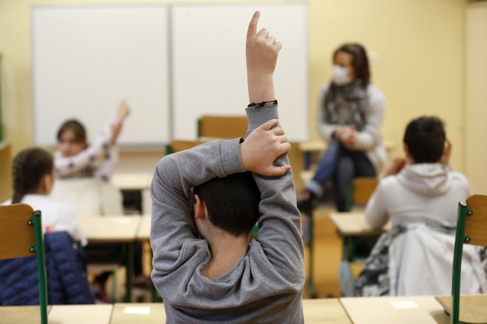 FILE - In this May 14, 2020 file photo, schoolchildren raise their fingers to answer their teacher Sandrine Albiez, wearing a face masks, in a school in Strasbourg, eastern France. France's government is admitting that not all classrooms can safely reopen Tuesday, Sept. 1, 2020 as planned. A persistent rise in virus infections is jeopardizing the government’s push to get France’s 12.9 million schoolchildren back into class.  (AP Photo/Jean-Francois Badias, File)