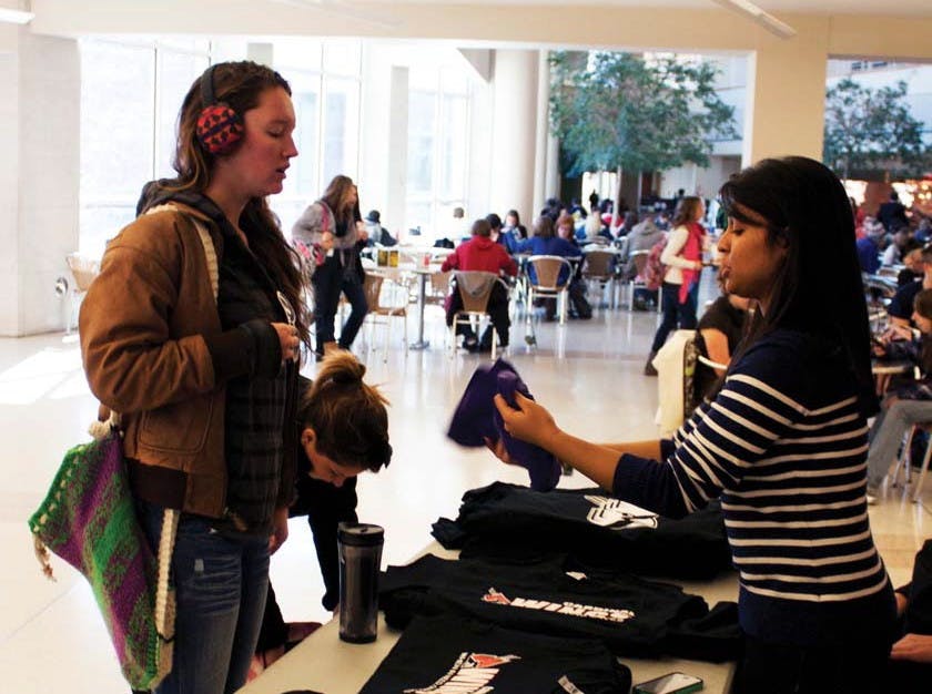 Sadie Sial, a senator with the Student Government Association, hands a shirt to a Ball State student Tuesday afternoon in the Atrium. The SGA is working to donate 1,000 T-shirts to the Muncie Mission through a shirt trade-in. DN PHOTO SADIE REECER