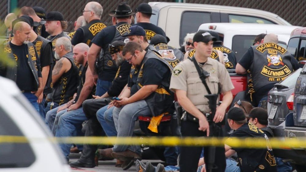 <p>A McLennan County deputy stands guard near a group of bikers in the parking lot of a Twin Peaks restaurant Sunday, May 17, 2015, in Waco, Texas. Photo by The Associated Press</p>