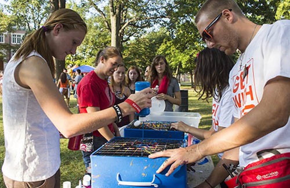 Freshman nursing major Ely Johnson pours paint onto a Frisbee during the UPB Quad Bash on Friday. DN PHOTO TAYLOR IRBY