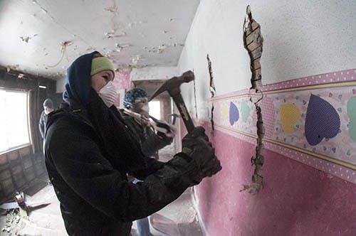 Sophomore architecture major Kelsi Stephens knocks down the plaster off a wall that they are renovating as part of a Habitat for Humanity initiative on Jan. 21. The local branch has formed a partnership with Ball State to offer an imersive learning oppurtunity for construction management, interior design and architecture majors. DN PHOTO JONATHAN MIKSANEK