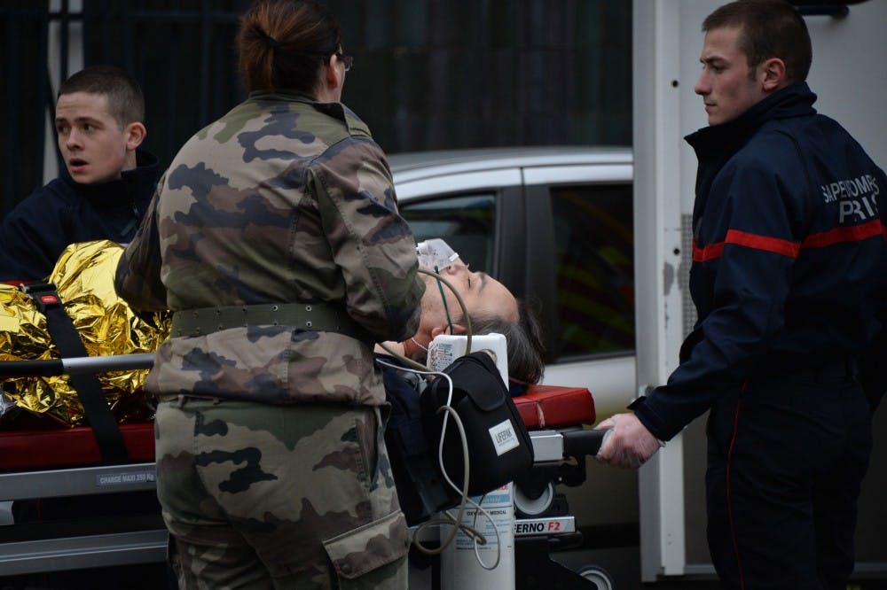Paramedics wheel a victim to an ambulance on Jan. 7, 2015 in Paris, France, after an attack where masked gunmen attacked the Paris office of French satirical magazine Charlie Hebdo, killing 12 people and injuring seven. At least two masked attackers opened fire with assault rifles in the office and exchanged shots with police in the street outside before escaping by car. President Hollande said there was no doubt it had been a terrorist attack 'of exceptional barbarity.' A major police operation is under way in the Paris area to catch the killers. (Panoramic/Zuma Press/TNS) 