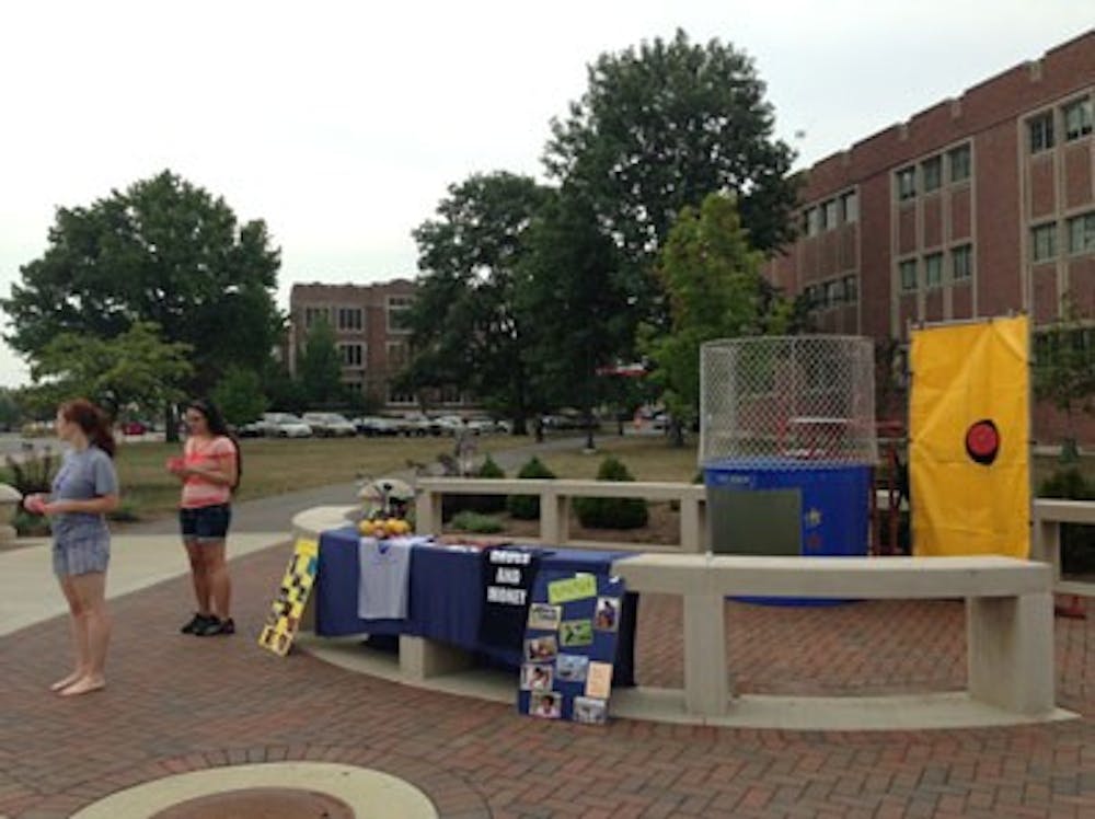 Members of Timmy Global Health man their dunk tank until 5 p.m. at the Scramble Light. People can purchase balls to dunk for $1, $3 and $5 to raise money for medical supplies for Ecuador and spread word about their club. DN PHOTO EMMA KATE FITTES