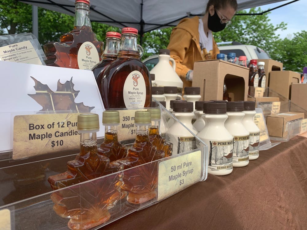 Katie Ambs, intern for Dragoonwood LLC, sets up maple syrup and honey products at the start of the farmers market, May 23, 2020, at Minnetrista. Ambs said Dragonwood&nbsp;has been busy at other farmers markets as well around Indiana. Jenna Gorsage, DN