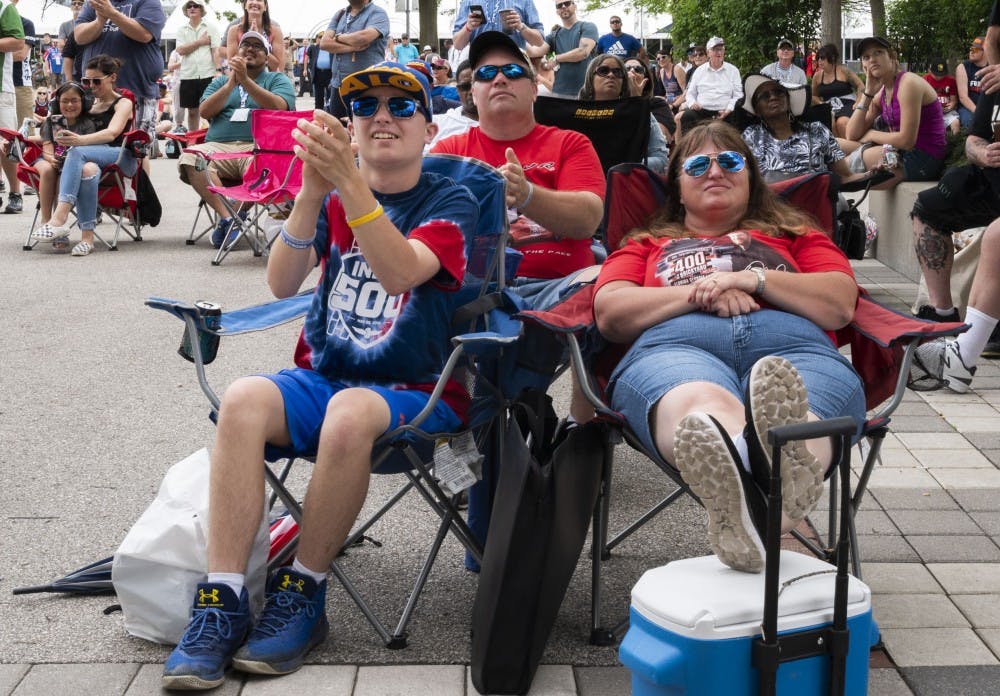 (Left to right) Christopher Burgess claps as he watches the racers run laps around the tracks at the Indianapolis Motor Speedway, outside the Pagoda's screen, May 26, 2019. Stephanie Amador, DN&nbsp;