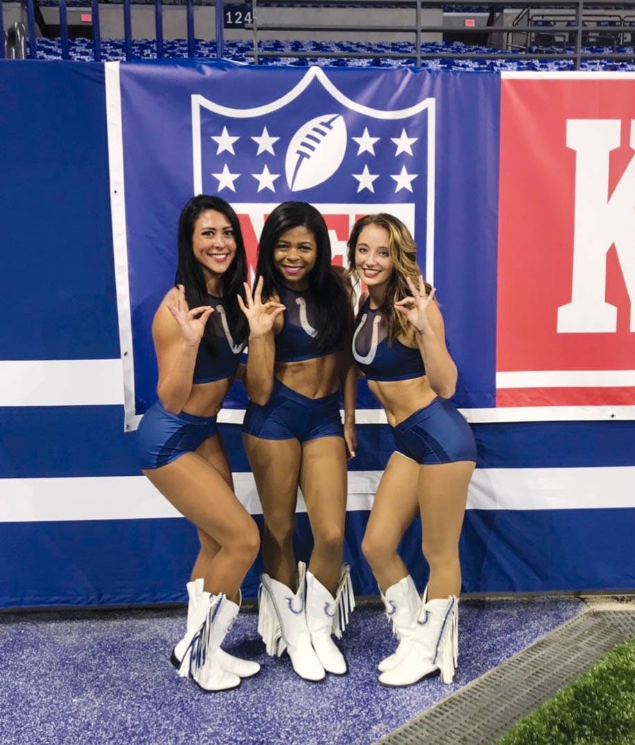 At an Indianapolis Colts game Sept. 9, 2018, former Indianapolis Colts cheerleaders Anne Cardimen (left), Ambria Ollie (middle) and Sarah Gilliom (right), strike a pose and sign Ball State’s ‘Chirp, chirp.’ Both Cardimen and Ollie are Ball State alumni and former dancers for Code Red Dance Team. Ambria Ollie, Photo Provided