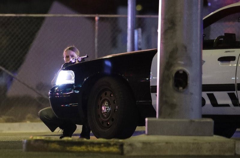 A police officer takes cover behind a police vehicle during a shooting near the Mandalay Bay resort and casino on the Las Vegas Strip Oct.1. Associated Press