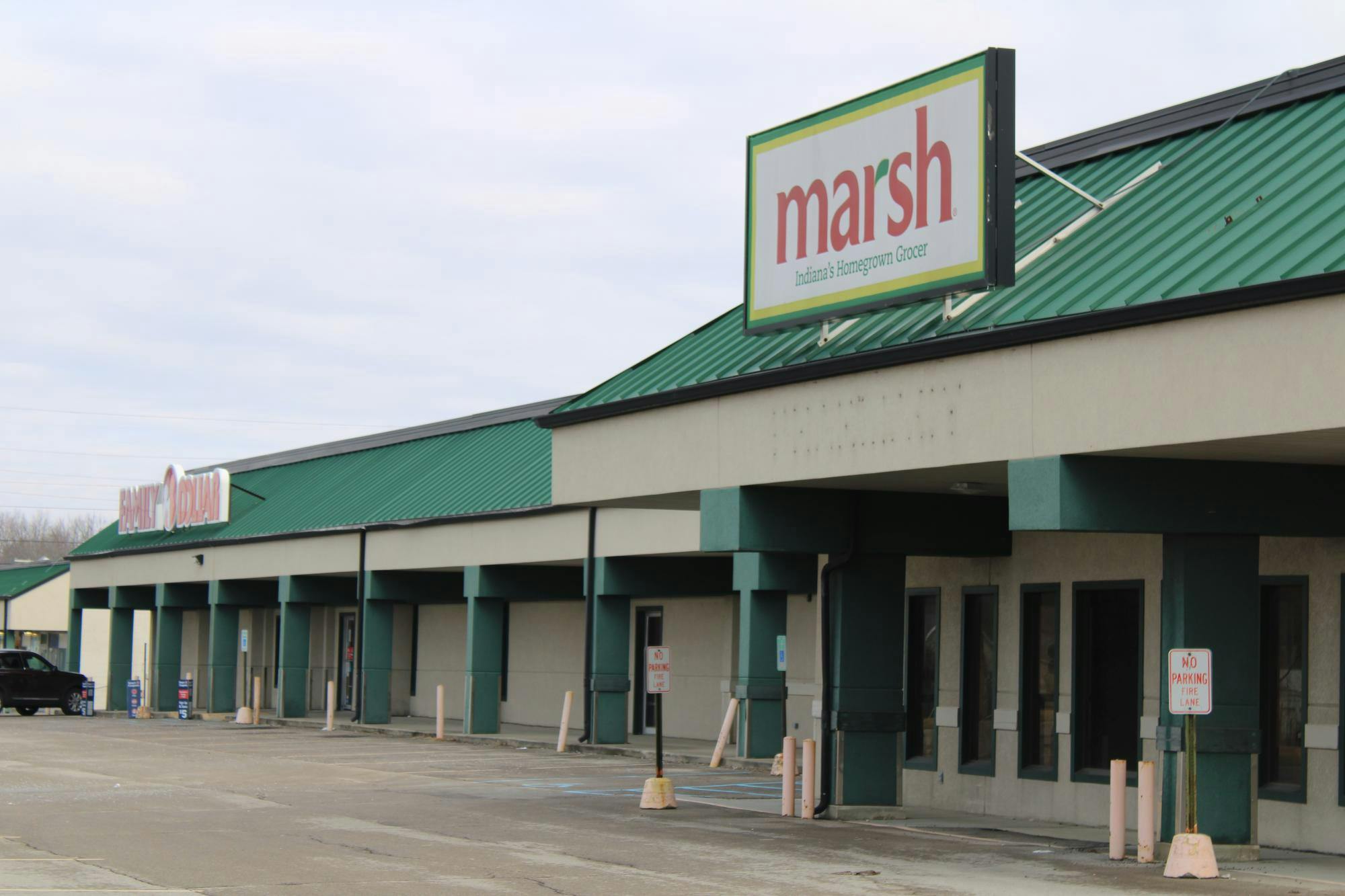 A pair of store signs jet out from the green roof of a shopping center on North Walnut Street in Muncie—one for the currently operating Family Dollar store and the other for the closed Marsh location. The former grocery hub has been untouched and unoccupied since 2017, and closures of its peer stores has opened the door for dollar store chains to capture the freed-up market share. Adam Altobella, photo provided.