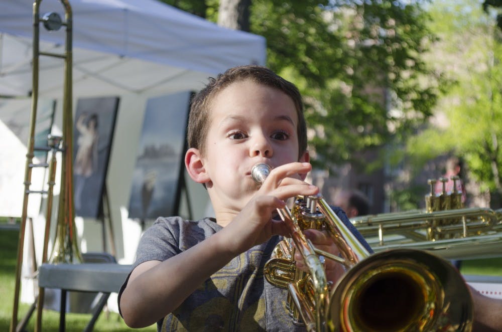 Noah Raymond, 6, plays the trumpet at the "Instrument Petting Zoo" at the Festival on the Green on June 14 at the Arts Terrace. DN PHOTO BREANNA DAUGHERTY 
