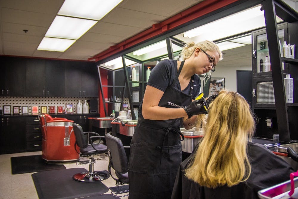 Abi Wright works on Kim Shockley's hair at the campus Hot Heads location on Aug. 31. Reagan Allen // DN