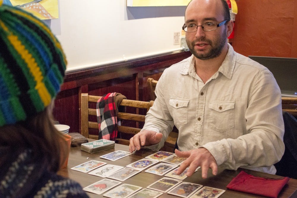 Ball State alumnus, Brandon Beeson, gives a student a tarot card reading on Jan. 12 at The Cup in the Villiage. During his readings, Beeson helps those that he performs reading for work through difficulties that they may be experiencing or difficult decisions that they are struggling with. DN PHOTO ALAINA JAYE HALSEY