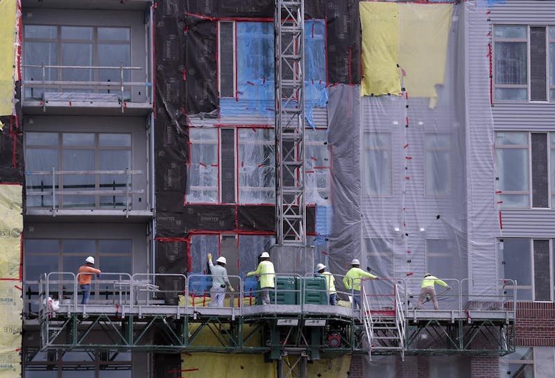 Construction workers perform tasks on an apartment building in 2019. Algorithmic price estimates, in which landlords might rely on complex data formulas to set rental rates, have become more popular in recent years, but lawsuits question whether the algorithms amount to price-fixing. (Photo by John Raoux/The Associated Press)