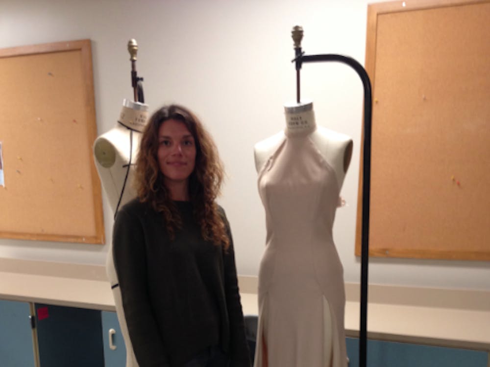 Juniper Boutique Owner Tamar Lask poses next to a gown created by Megan Bright for&nbsp;this upcoming spring semester's fashion show. PHOTO BY GABRIELLA HARBRIDGE