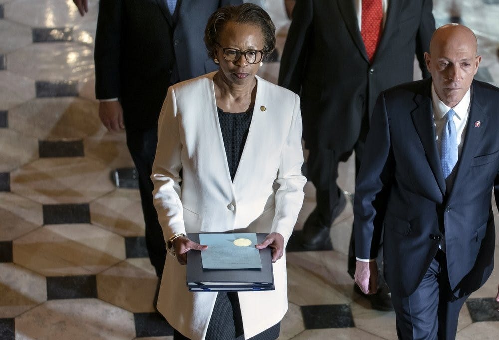 Clerk of the House Cheryl Johnson, center, with House Sergeant at Arms Paul Irving, right, pass through Statuary Hall at the Capitol to deliver the articles of impeachment against President Donald Trump to the Senate, on Capitol Hill in Washington, Wednesday, Jan. 15, 2020. (AP Photo/J. Scott Applewhite)