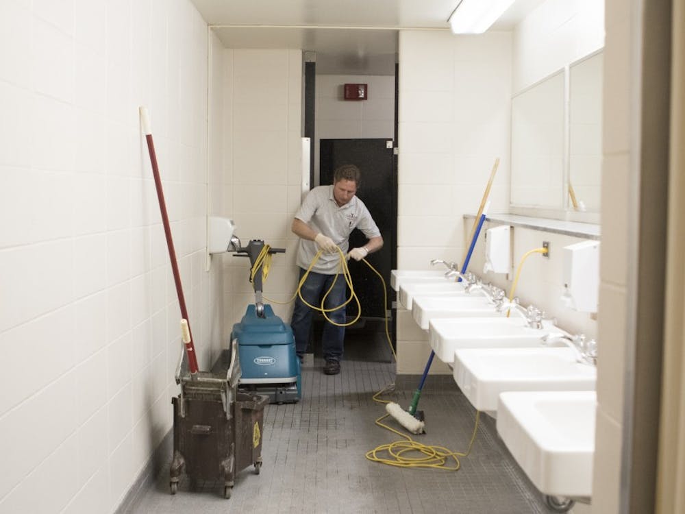 Custodian Greg Hobson mops and cleans one of the men's bathrooms on the LaFollette Complex's first floor. With the students gone, Hobson has the chance to scrub and wax the stairwells and landings.DN PHOTO JORDAN HUFFER
