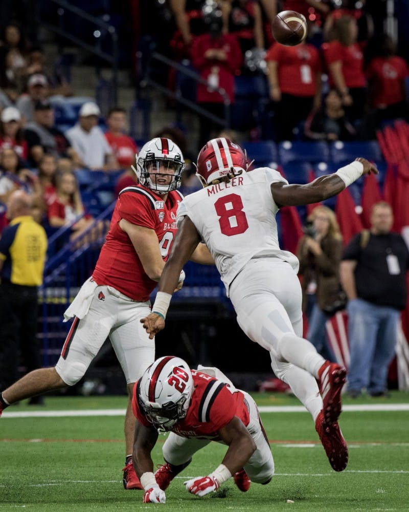 Ball State redshirt junior quarterback Drew Plitt throws a pass as an Indiana defender breaks past the line of scrimmage Aug. 31, 2019, in Lucas Oil Stadium in Indianapolis. After a close first half, Indiana walked away defeating the Cardinals, 34-24, in the season opener. Eric Pritchett, DN