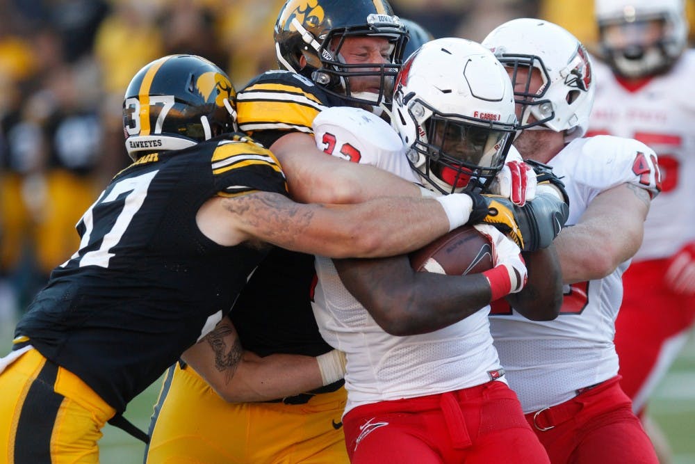 Ball State cornerback Quintin Cooper gets tackled by Iowa defensive lineman Drew Ott and defensive back John Lowdermilk on Sept. 6 in Kinnick Stadium. Iowa defeated Ball State, 17-13. (The Daily Iowan/Rachael Westergard)
