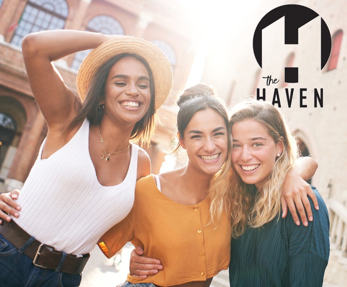 Three happy female friends having fun outdoors in summer vacations at city. Portrait of smiling woman hugging looking at camera together. High quality photo