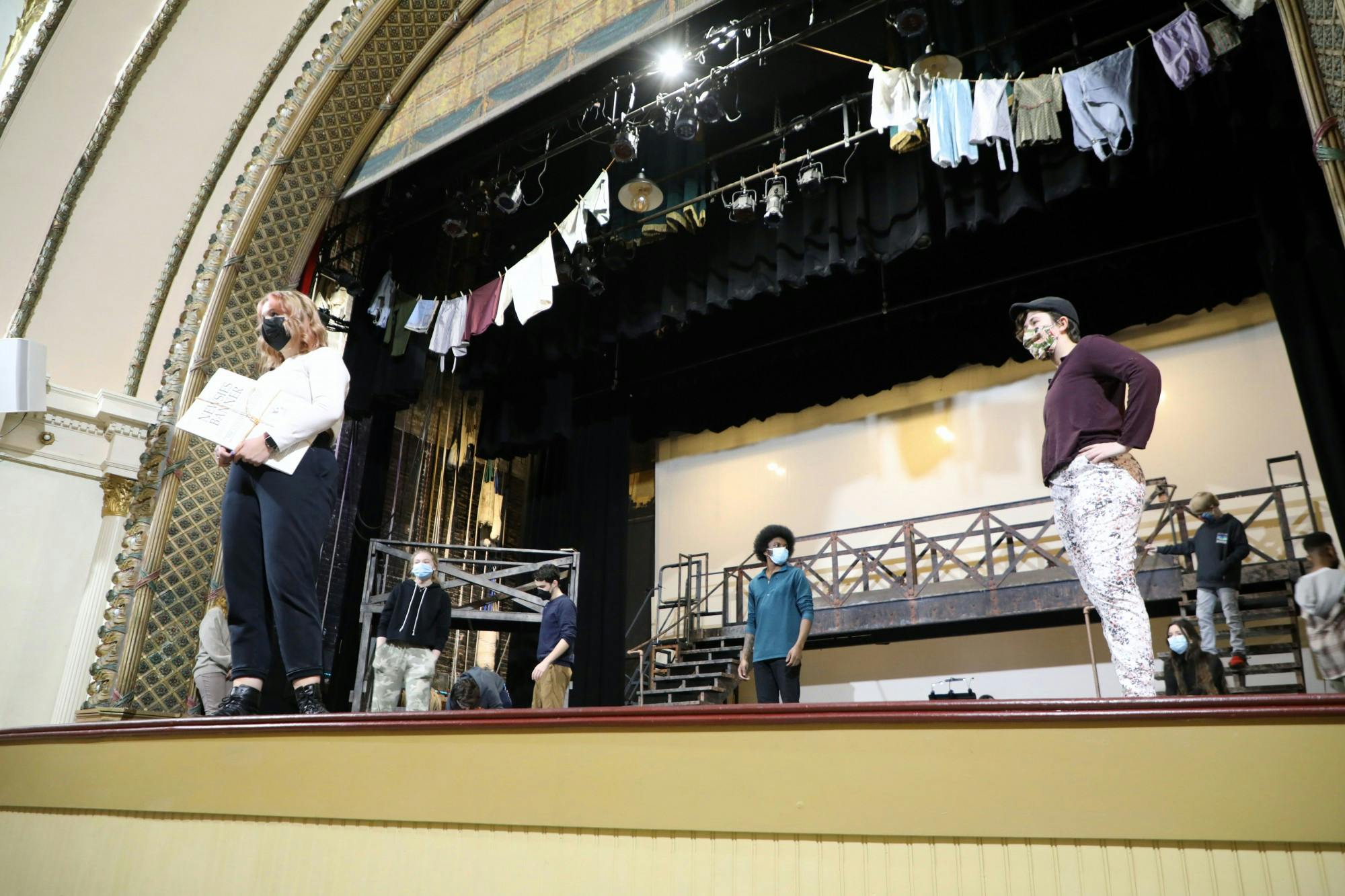 Natalie Meyer, Ball State junior theatre creation major, holds a &quot;Newsies Banner&quot; onstage while listening to Brittany Covert, director of &quot;Newsies,&quot; alongside fellow cast members Feb. 8. &quot;Newsies&quot; is a musical loosely based on the newsboys&#x27; strike of 1899. Maya Wilkins, DN