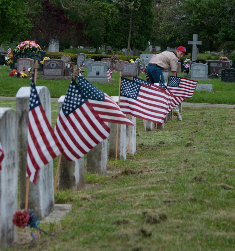 <p>A boy scout plants a flag May 21, 2019, at the Beech Grove Cemetery. A troop from Boy Scouts of America planted American flags next to the gravestones of military veterans before Memorial Day. <strong>Blake Chapman, DN</strong></p>