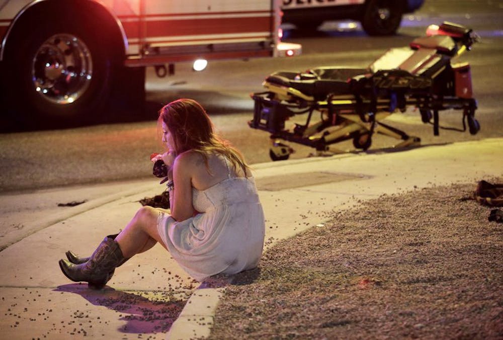 A woman sits on a curb at the scene of a shooting outside of a music festival along the Las Vega Strip Oct. 2. in Las Vegas. AP News, Photo Courtesy