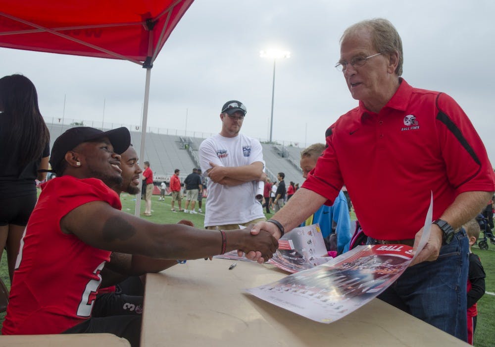 Mayor Dennis Tyler shakes hands with a football player after getting his poster signed at Fan Jam on Aug. 16 at Scheumann Stadium. DN PHOTO BREANNA DAUGHERTY