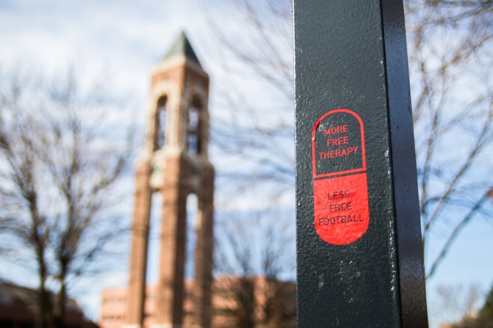 Pill stickers are scattered around campus that say "More Free Therapy, Less Free Football." Reagan Allen // DN