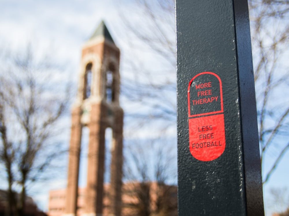 Pill stickers are scattered around campus that say "More Free Therapy, Less Free Football." Reagan Allen // DN