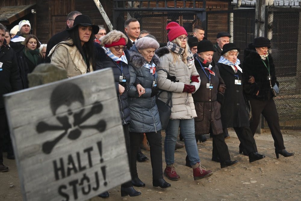 Poland's President Andrzej Duda walks along with survivors through the gates of the Auschwitz Nazi concentration camp Jan. 27, 2020, in Oswiecim, Poland. Survivors of the Auschwitz-Birkenau death camp gathered for commemorations marking the 75th anniversary of the Soviet army's liberation of the camp, using the testimony of survivors to warn about the signs of rising anti-Semitism and hatred in the world today. (AP Photo/Czarek Sokolowski)