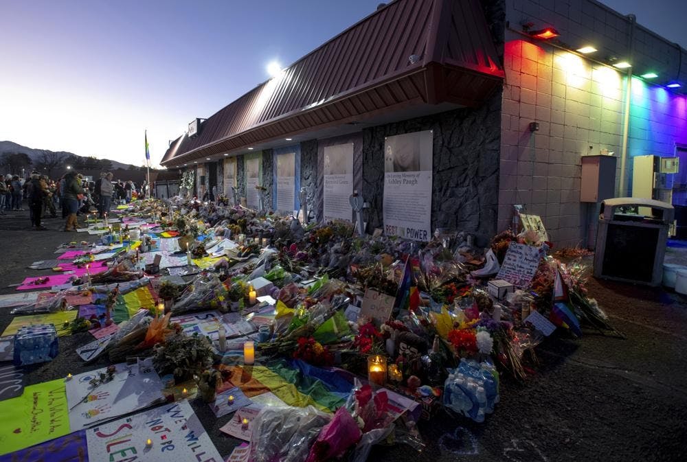 <p>File-Mourners gather outside Club Q to visit a memorial, which has been moved from a sidewalk outside of police tape that was surrounding the club, on Friday, Nov. 25, 2022, in Colorado Spring, Colo. The suspect accused of entering the gay nightclub clad in body armor and opening fire with an AR-15-style rifle, killing five people and wounding 17 others, is set to appear in court again Tuesday, Dec. 6 to learn what charges prosecutors will pursue in the attack, including possible hate crime counts. (Parker Seibold/The Gazette via AP, File)</p>