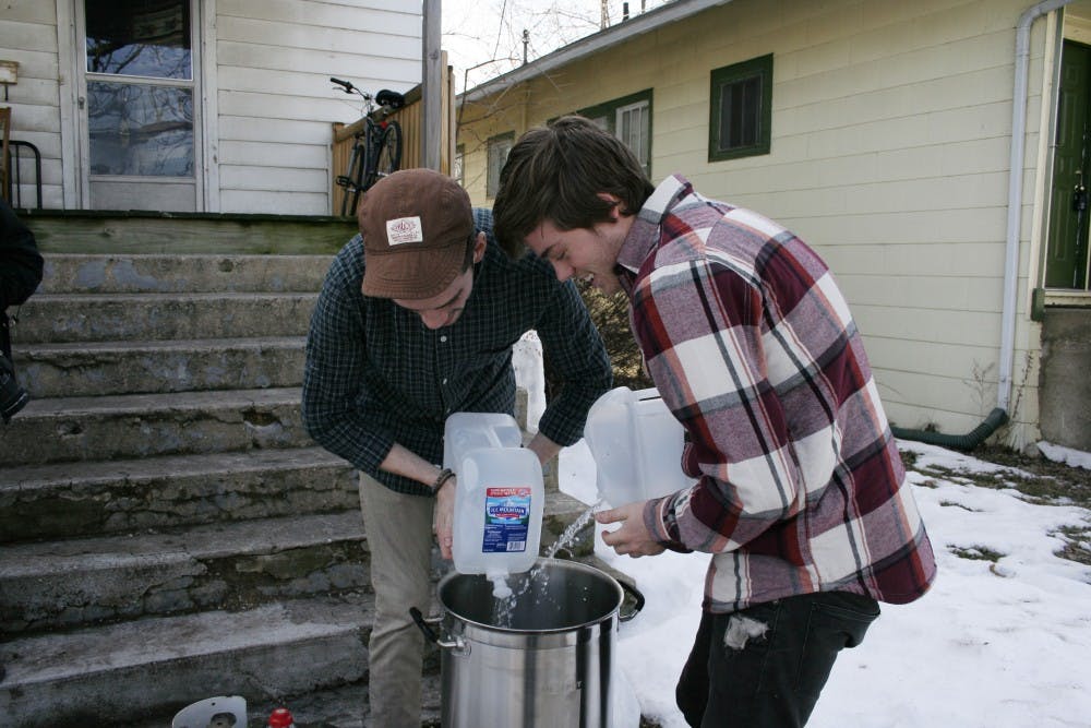 Tyler Varnau, a senior journalism graphics major and Kyle Little pour 5.5 gallons of water into a pot to heat. This is the first step for their home-brewing process. DN PHOTO LAUREN CHAPMAN