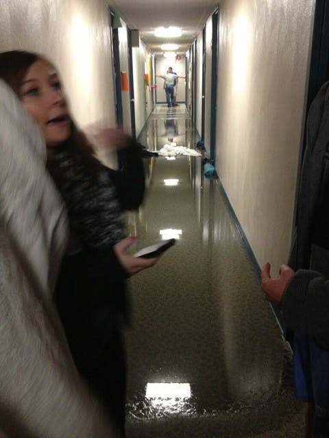 Students watch as custodians assess how to clean up after flooding on the first floor of Woody/Shales late March 12, 2013. A hot water pipe burst on the second floor, forcing students to temporarily evacuate. PHOTO PROVIDED BY LANDEN KISER