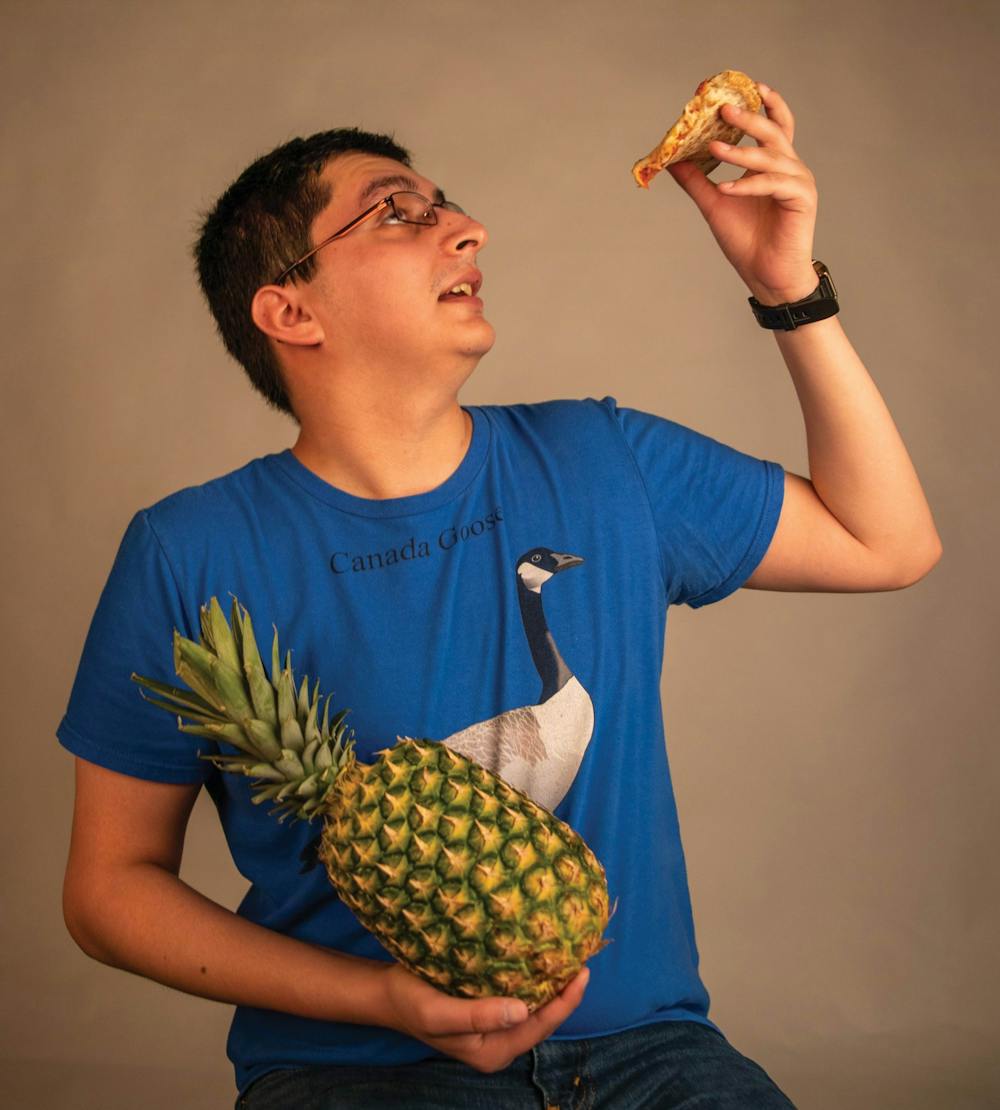 <p>Senior creative writing major Ian Roesler poses for a photo April 7, 2021, in the photojournalism studio. According to data from a 2019 YouGov poll, 12 percent of Americans like pineapple as a pizza topping. <strong>Jaden Whiteman, DN Illustration</strong></p>