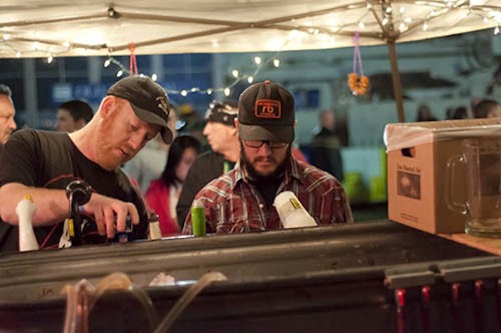 Brian Howensten pours a beer from an outdoor stand as he works with another vendor. Muncie Gras is this Saturday. DN FILE PHOTO COREY OHLENKAMP