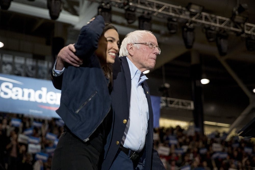 Democratic presidential candidate Sen. Bernie Sanders, I-Vt., accompanied by Rep. Alexandria Ocasio-Cortez, D-N.Y., left, takes the stage at campaign stop at the Whittemore Center Arena at the University of New Hampshire, Feb. 10, 2020, in Durham, N.H. (AP Photo/Andrew Harnik)