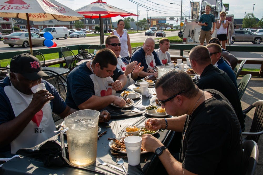 Members of the Muncie Fire Department (left) and Muncie Police Department (right) eat and laugh as they compete in the fifth annual Battle of the Badges rib-eating contest Sept. 18, 2018, at Texas Roadhouse in Muncie. The winner of the contest won a monetary award which is donated to a charity of their choosing. Leslie Gartrell,DN