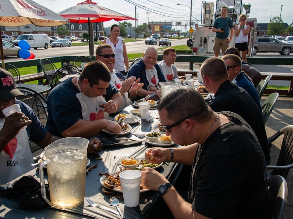 Members of the Muncie Fire Department (left) and Muncie Police Department (right) eat and laugh as they compete in the fifth annual Battle of the Badges rib-eating contest Sept. 18, 2018, at Texas Roadhouse in Muncie. The winner of the contest won a monetary award which is donated to a charity of their choosing. Leslie Gartrell,DN
