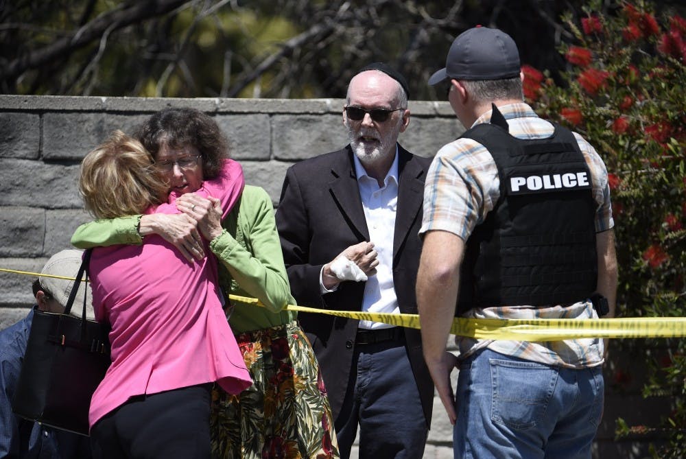 Two people hug as another talks to a San Diego County Sheriff's deputy outside of the Chabad of Poway synagogue, Saturday, April 27, 2019, in Poway, Calif. A man opened fire inside the synagogue near San Diego as worshippers celebrated the last day of a major Jewish holiday. (AP Photo/Denis Poroy)