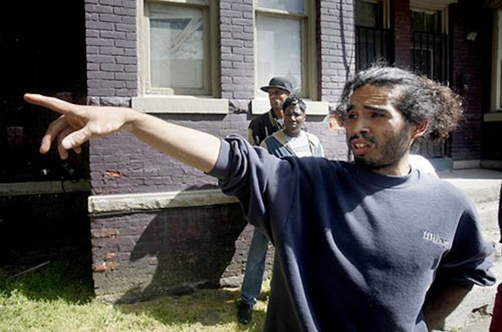 Hector Lugo points to a house police searched during an investigation in Cleveland, Ohio, on May 7. Three women who vanished separately about a decade ago were rescued from the home. MCT PHOTO