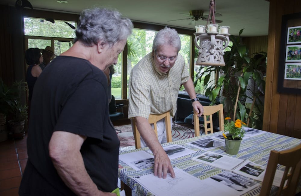 <p>Greg Graham shares with a tour participant the original house plans and old photographs in his dining room. DN PHOTO BREANNA DAUGHERTY</p>