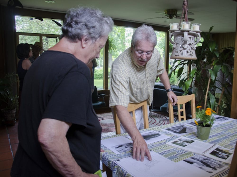 Greg Graham shares with a tour participant the original house plans and old photographs in his dining room. DN PHOTO BREANNA DAUGHERTY