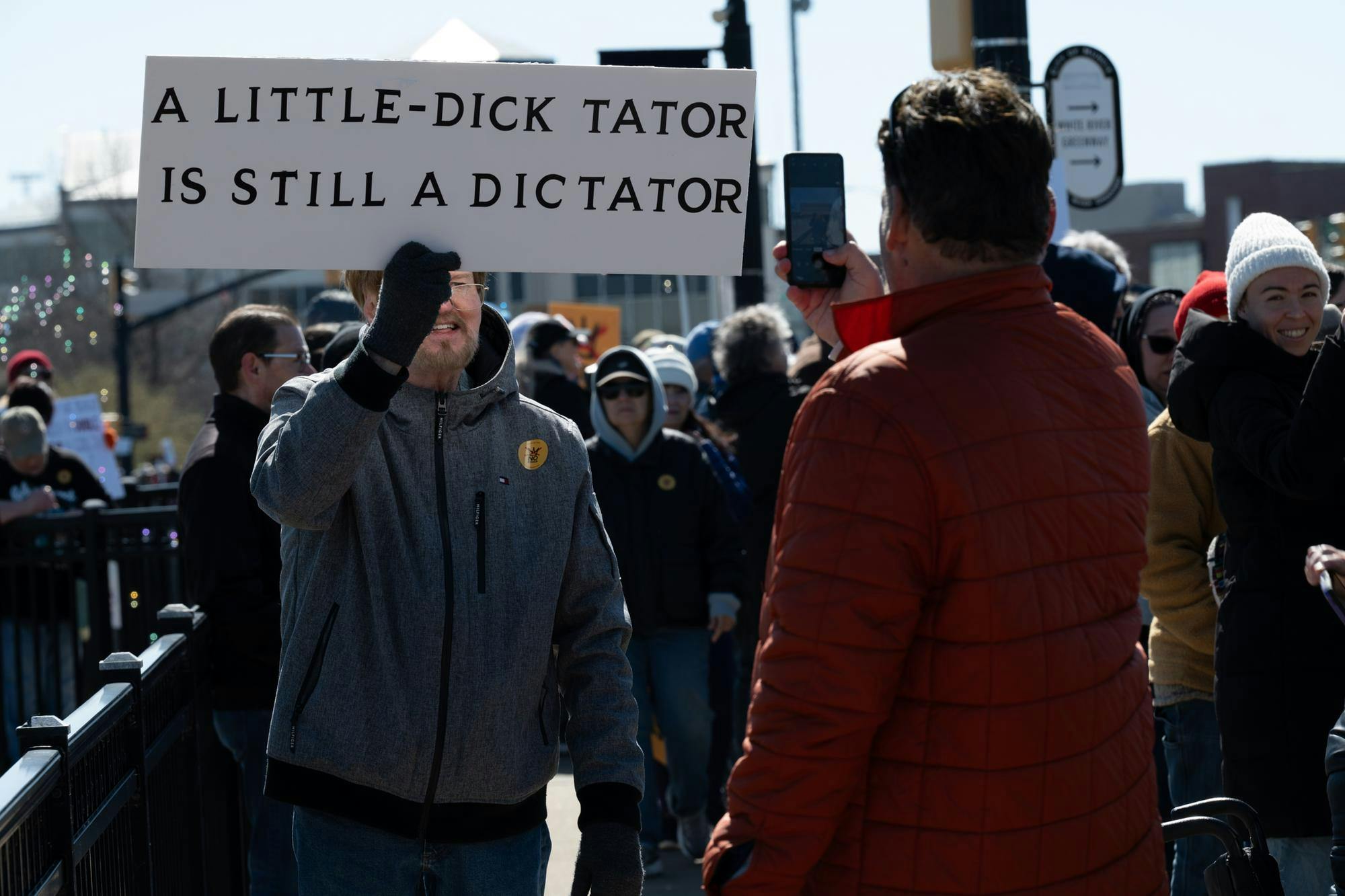 A protester hoists a sign while another snaps a photo during the ‘No Kings 3’ protest March 28 at the Fallen Heroes Memorial Bridge. Ryan Fleek, DN