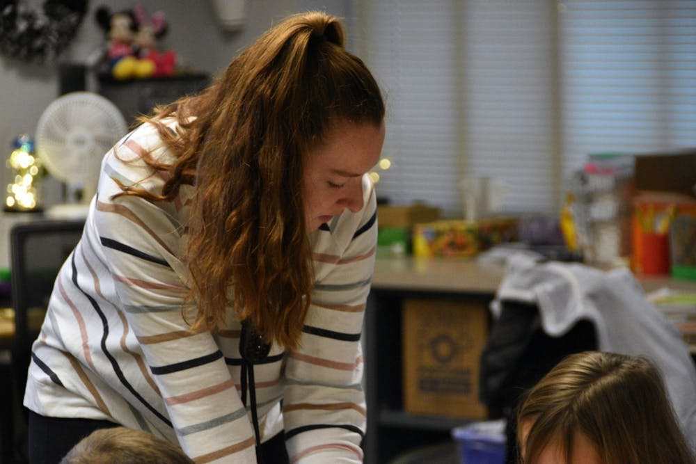 Fourth-year elementary education major Alissa Kizer helps a student with her assignment at Carey Ridge Elementary School Dec. 2. The students were practicing the difference between proper and common nouns. Ella Howell, DN