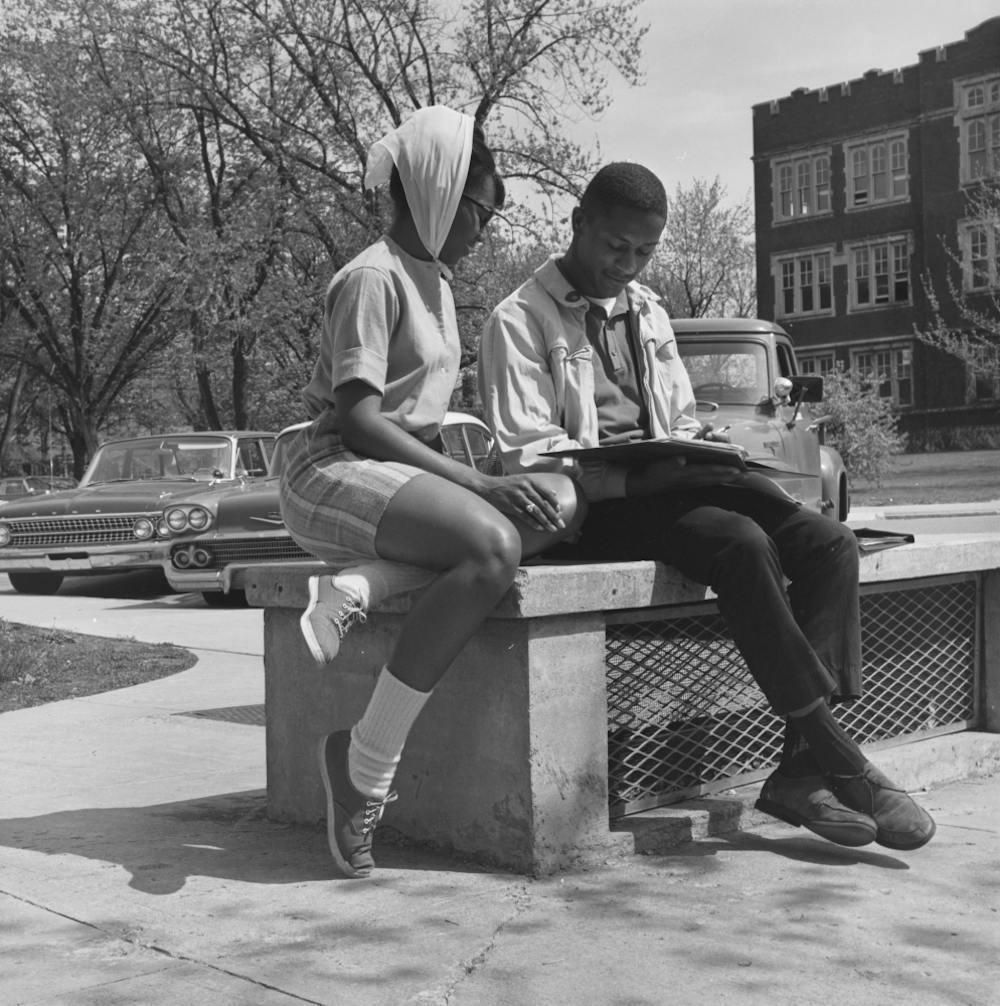<p>Two students read on a bench along a circular drive near the Administration Building in 1963 in Muncie, IN. Photo provided, Michael Szajewski.</p>