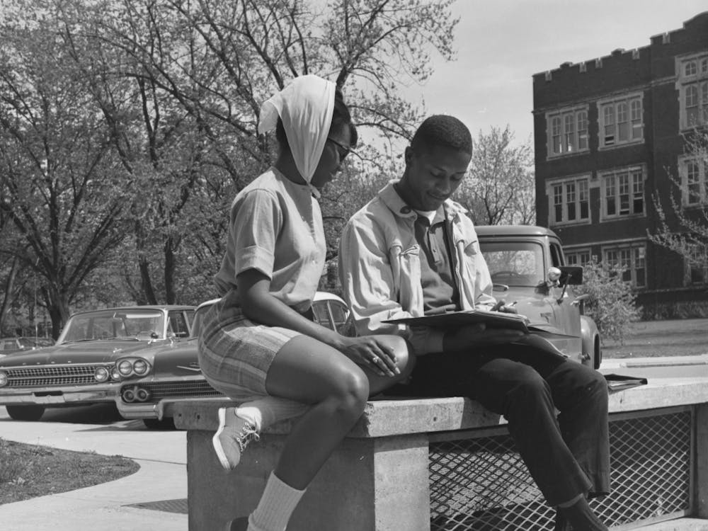Two students read on a bench along a circular drive near the Administration Building in 1963 in Muncie, IN. Photo provided, Michael Szajewski.