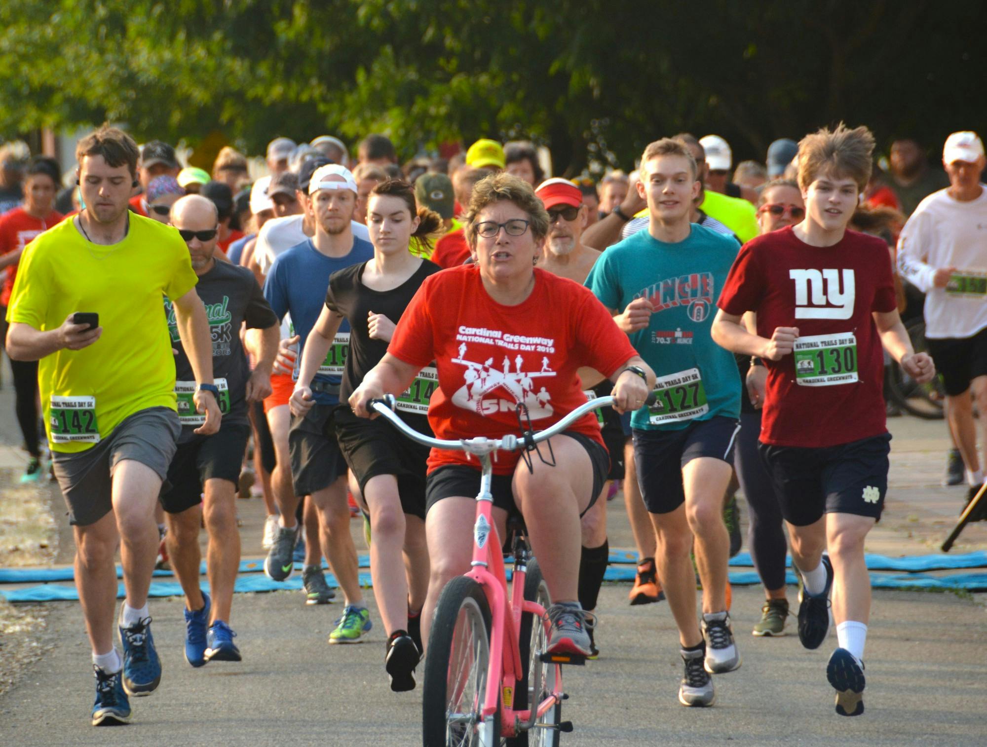 A pacer on a bicycle leads the pack of runners at a previous Cardinal Greenways 5K. For 2021, Cardinal Greenways is hosting joint races in Muncie and Marion County. Brian Schleeper/ Cardinal Greenways, Photo Provided