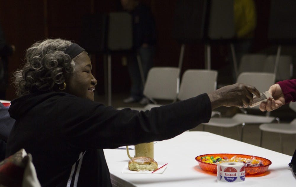 Poll judge Anna Johnson returns an ID to a voter on Election Day. 
