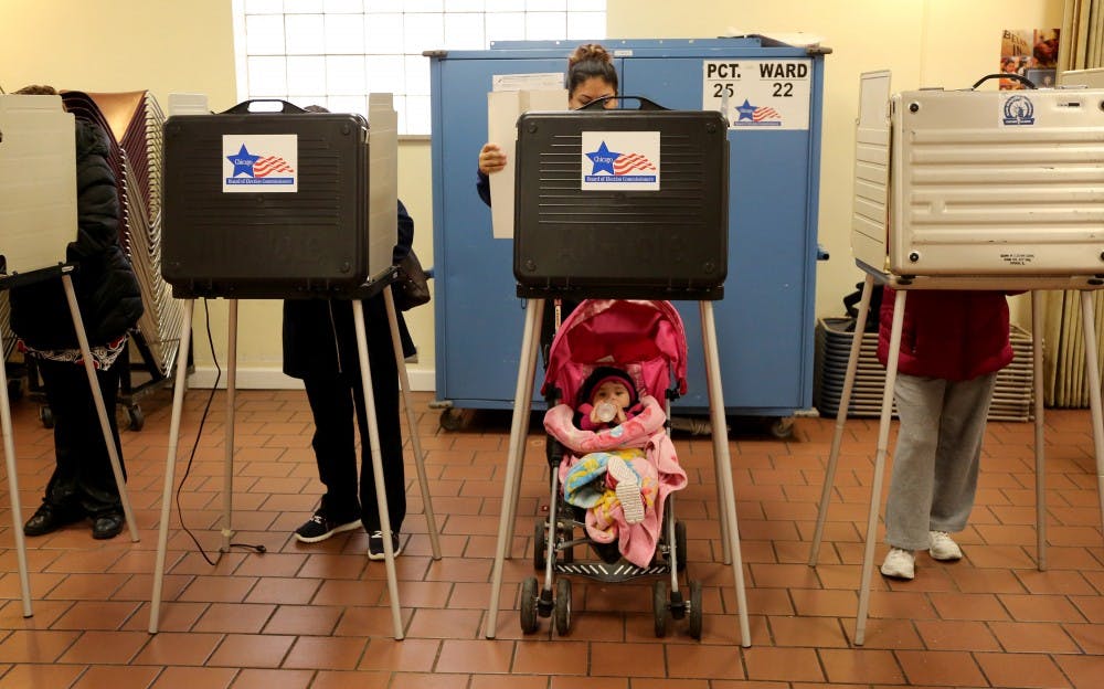Voter Adriana Reyes, center, finishes up casting her vote as her 9 month old baby, Ariana, waits during the voting for the primary elections at St. Agnus Bishop Manz Hall on March 15, 2016 in Chicago. (Antonio Perez/Chicago Tribune/TNS) 
