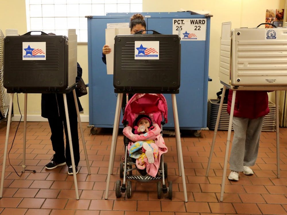 Voter Adriana Reyes, center, finishes up casting her vote as her 9 month old baby, Ariana, waits during the voting for the primary elections at St. Agnus Bishop Manz Hall on March 15, 2016 in Chicago. (Antonio Perez/Chicago Tribune/TNS) 